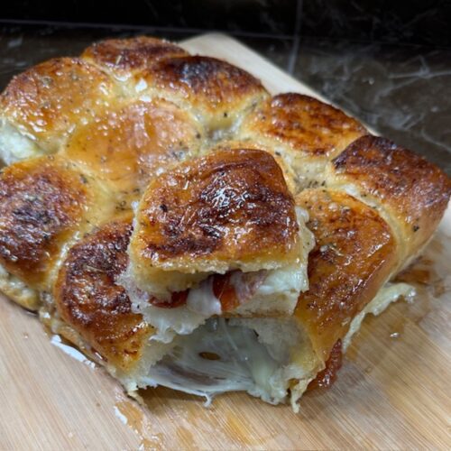 Pepperoni pizza sliders on a wooden cutting board.
