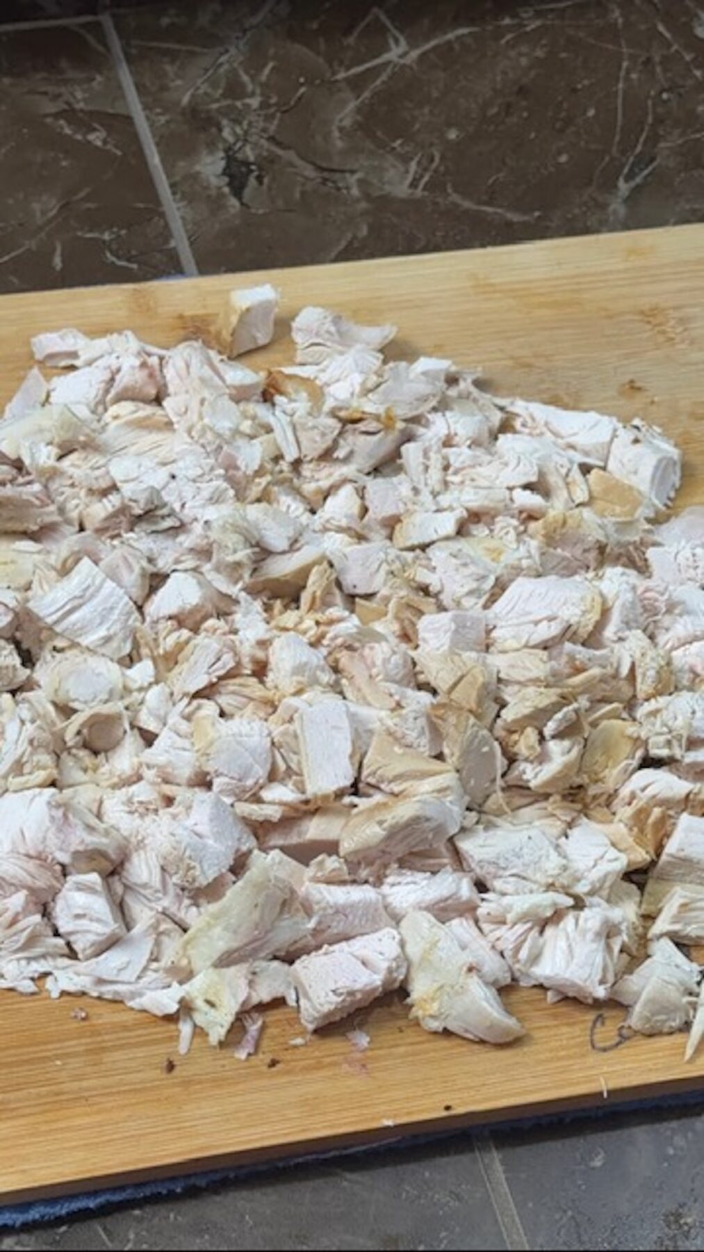 A cutting board with chopped chicken.