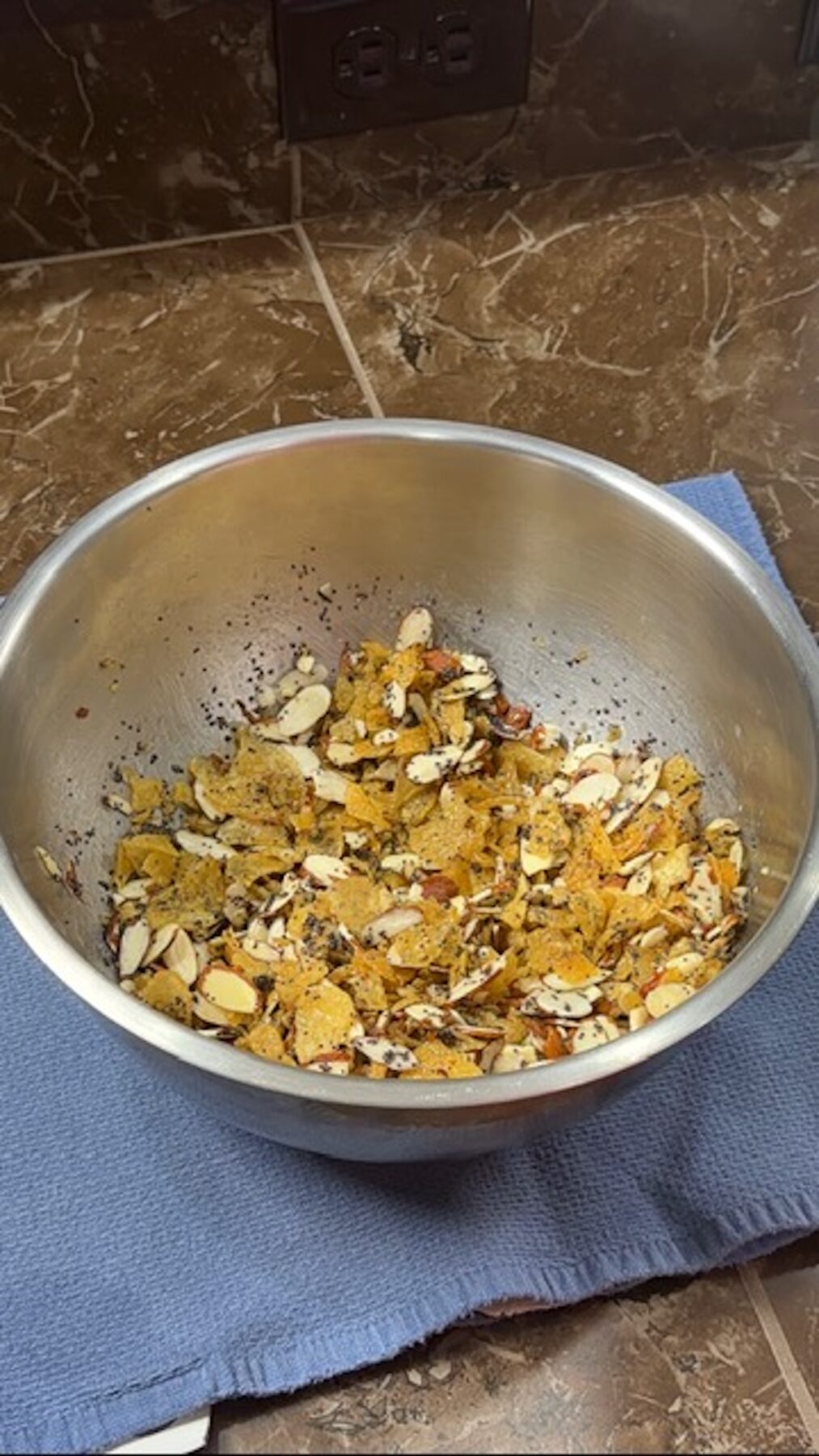 A metal bowl with poppyseed chicken cracker topping.