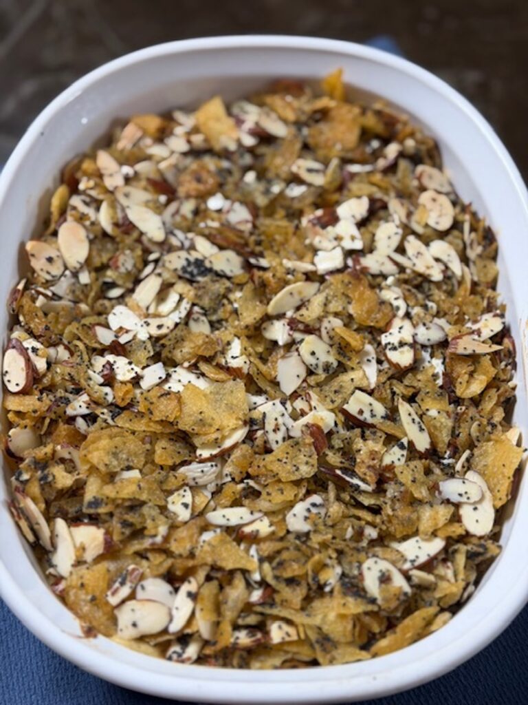 Close up image of a white casserole dish with poppyseed chicken casserole.