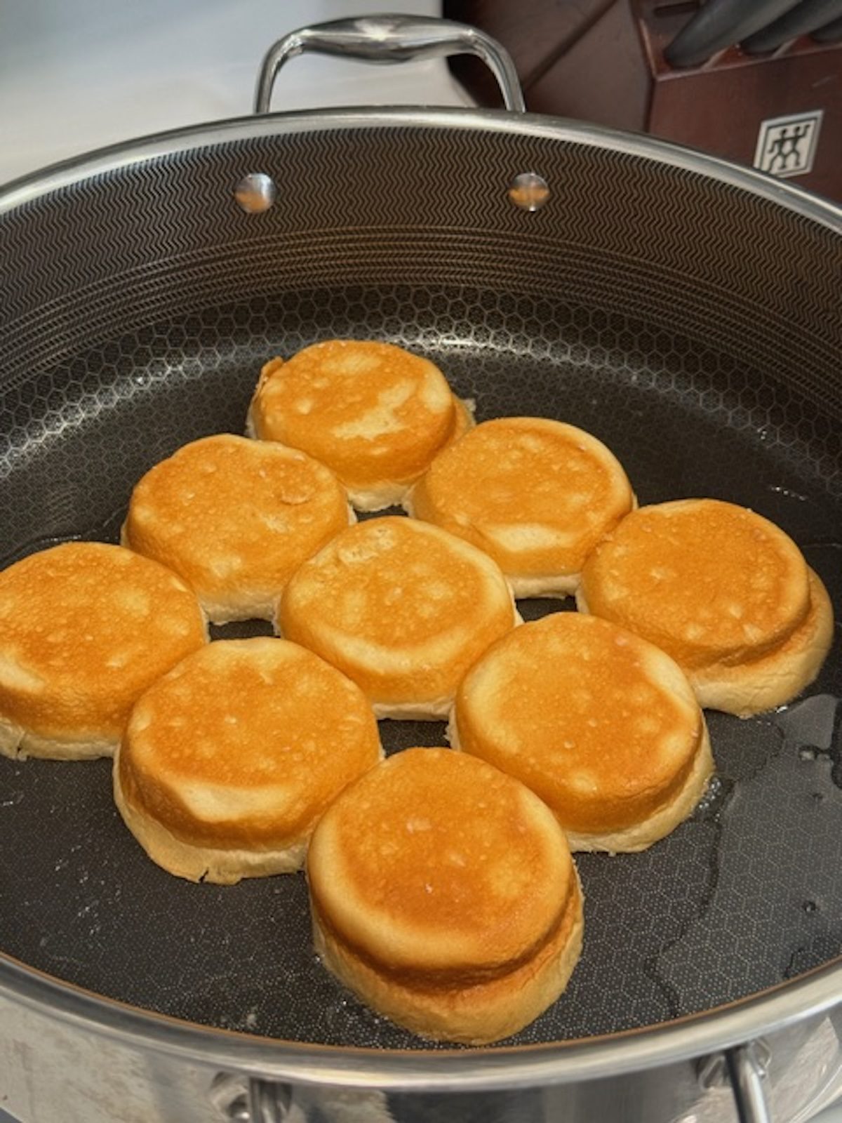 A large pan with slider buns toasting.