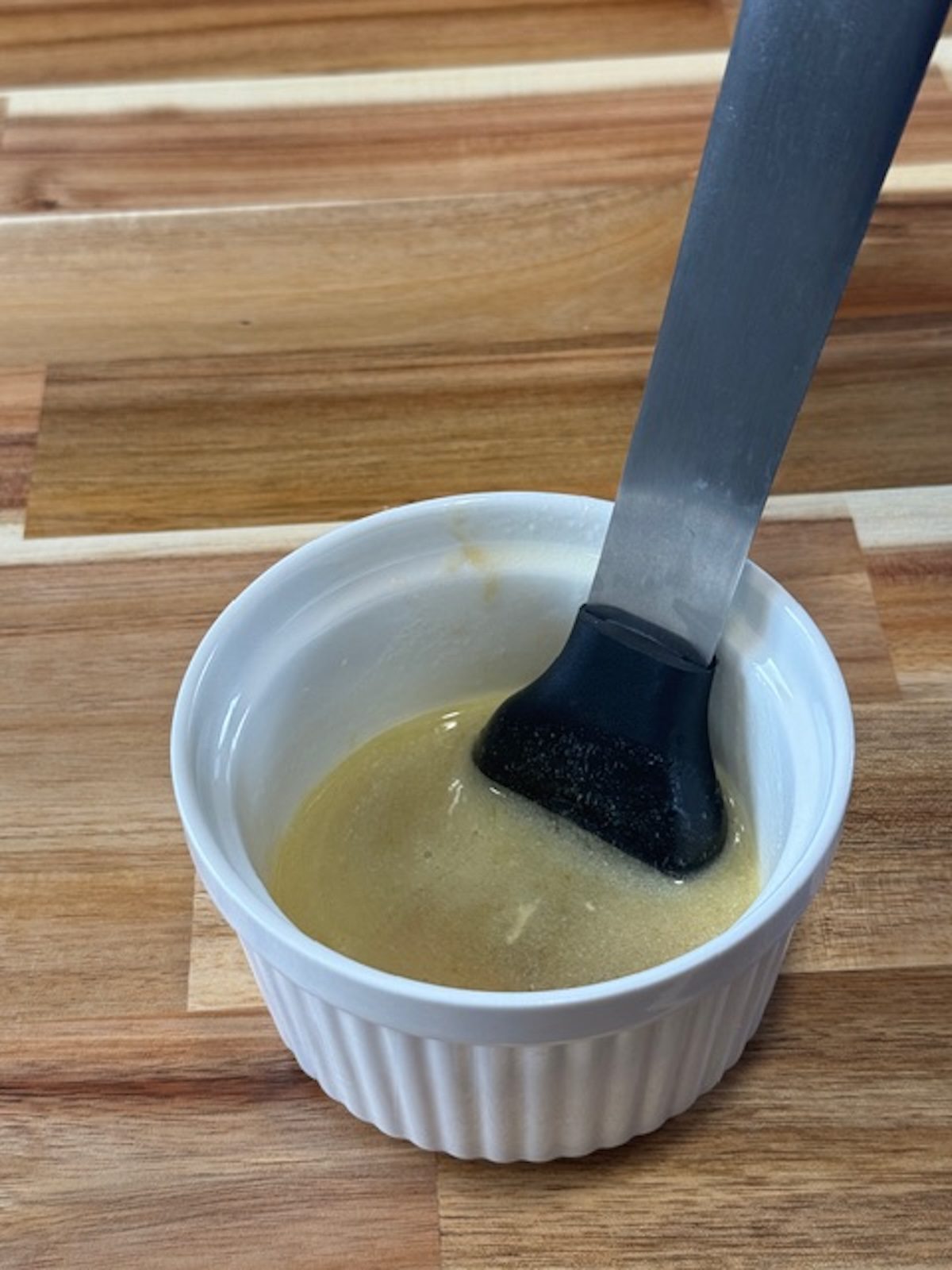 A white ramekin with brush for sauce for chicken bacon ranch sliders.