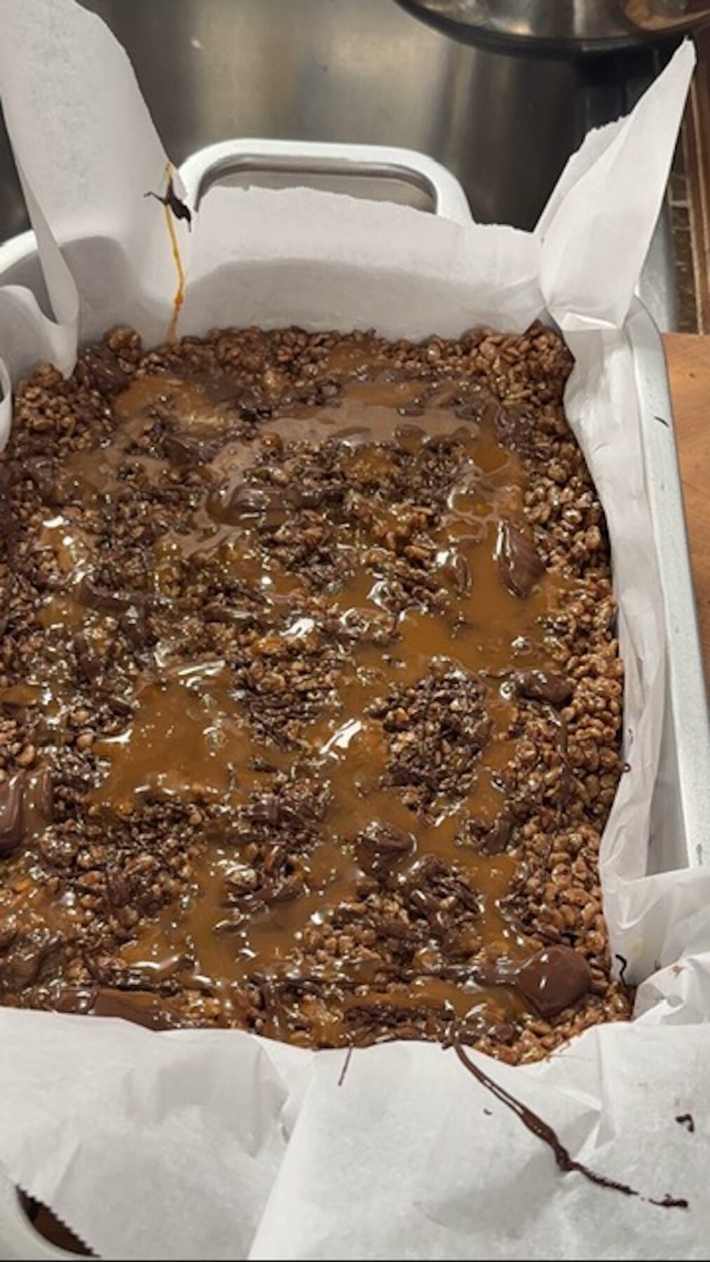 Chocolate rice krispie treats pressed into the baking dish with chocolate on top.