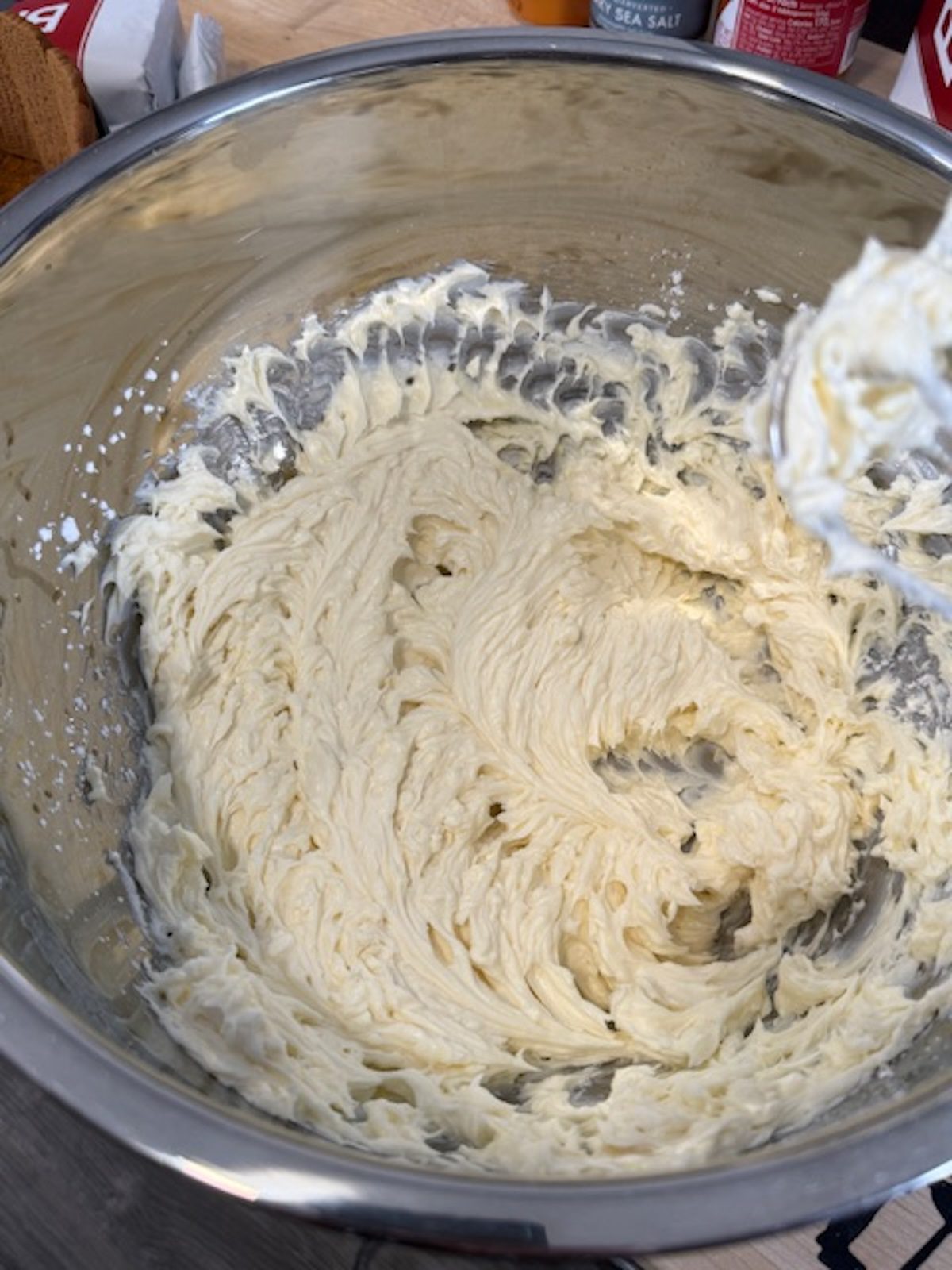 A metal bowl with cream cheese beating for no bake biscoff cheesecake.