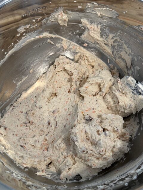 A glass bowl with whipped carrot cake cheesecake mixture.