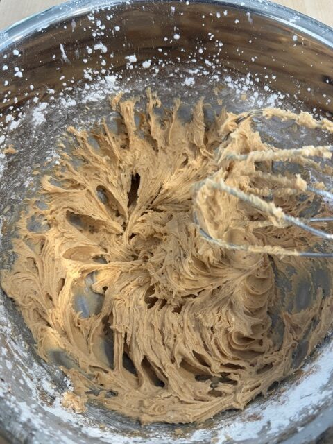 A meta bowl with no bake carrot cake cheese mixture being whipped with hand mixer.