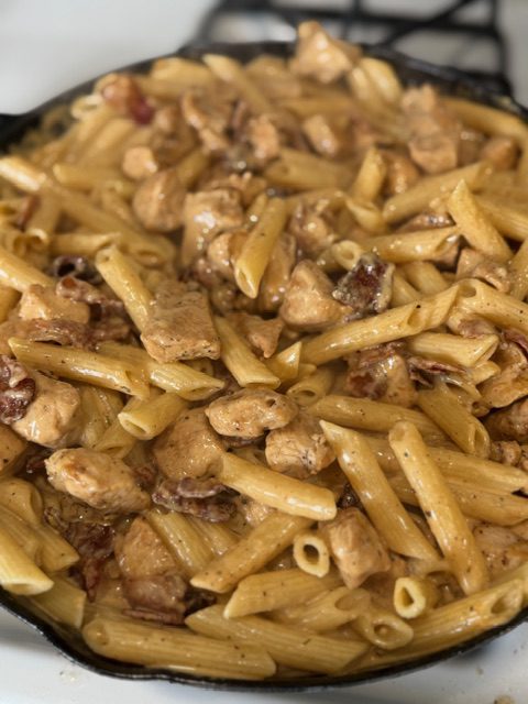 A cast iron skillet with crack chicken pasta.