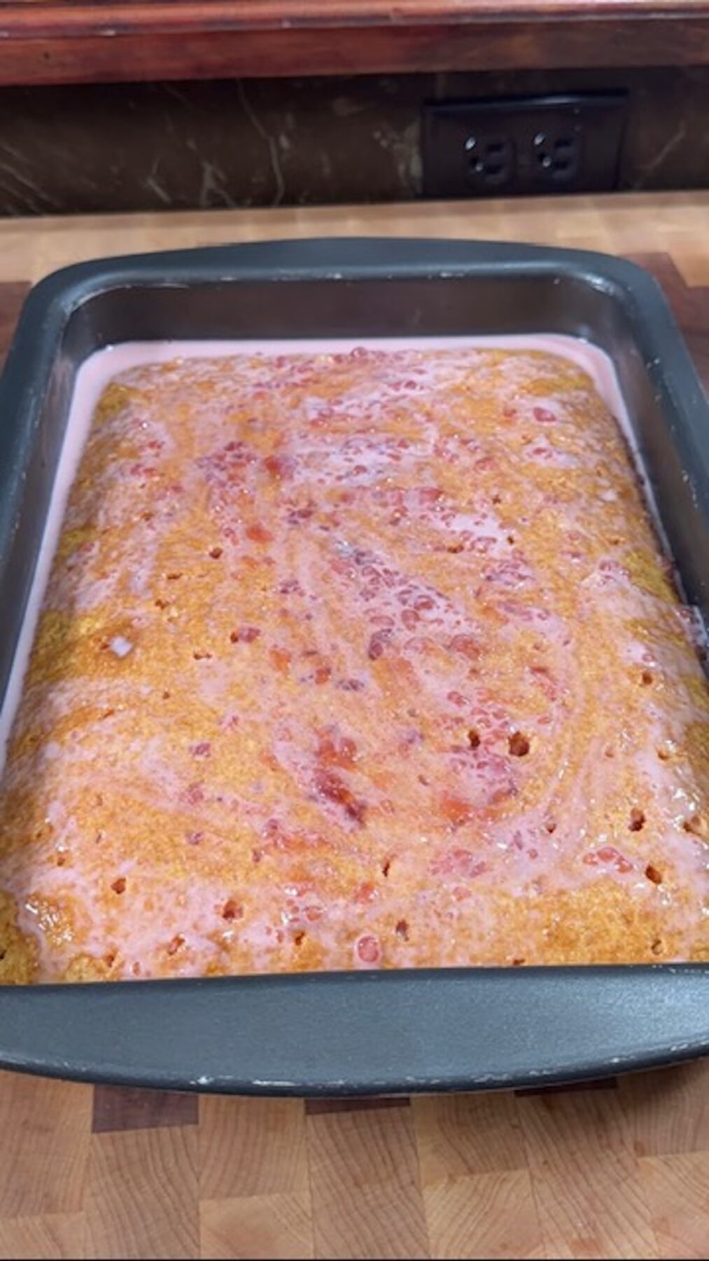 A baked strawberry cake with strawberry milk mixture soaking on top.