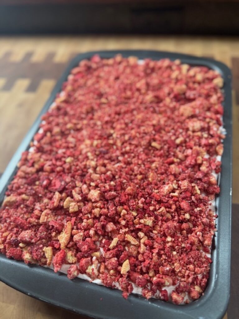 Close up image of strawberry tres leches cake with strawberry crunch topping.