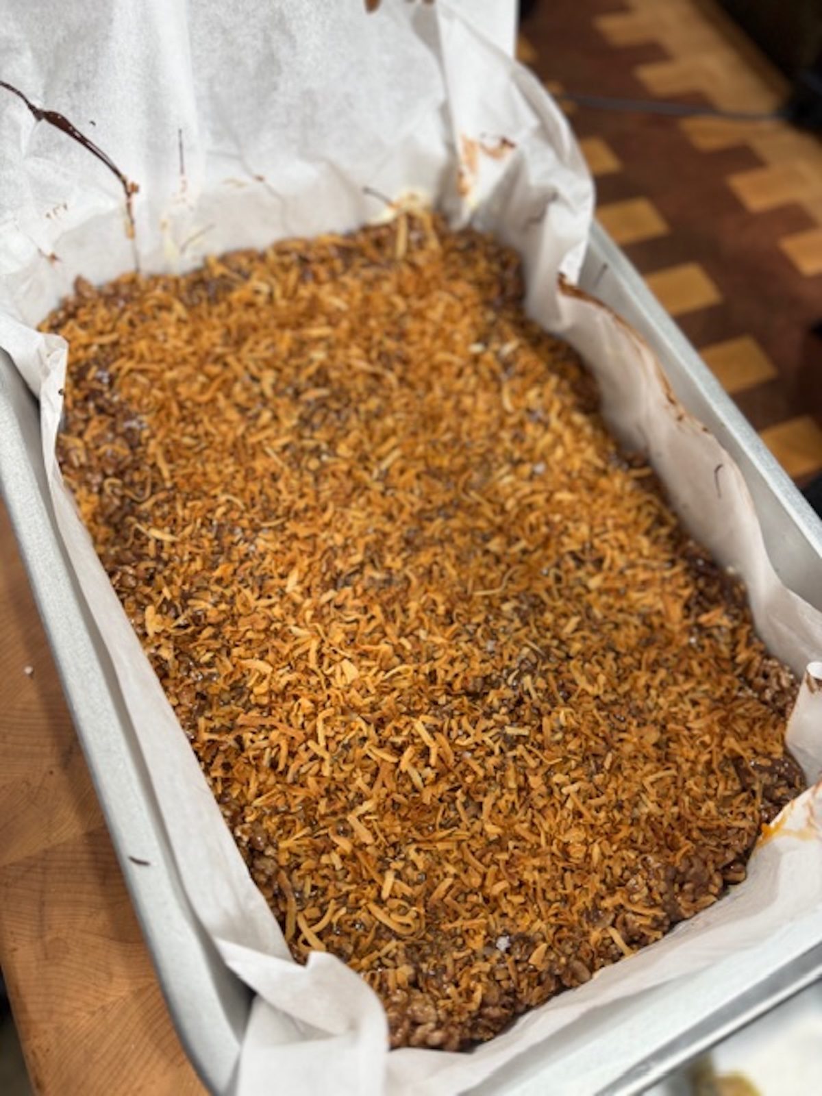 Chocolate rice krispie treats pressed into a baking dish with coconut on top.