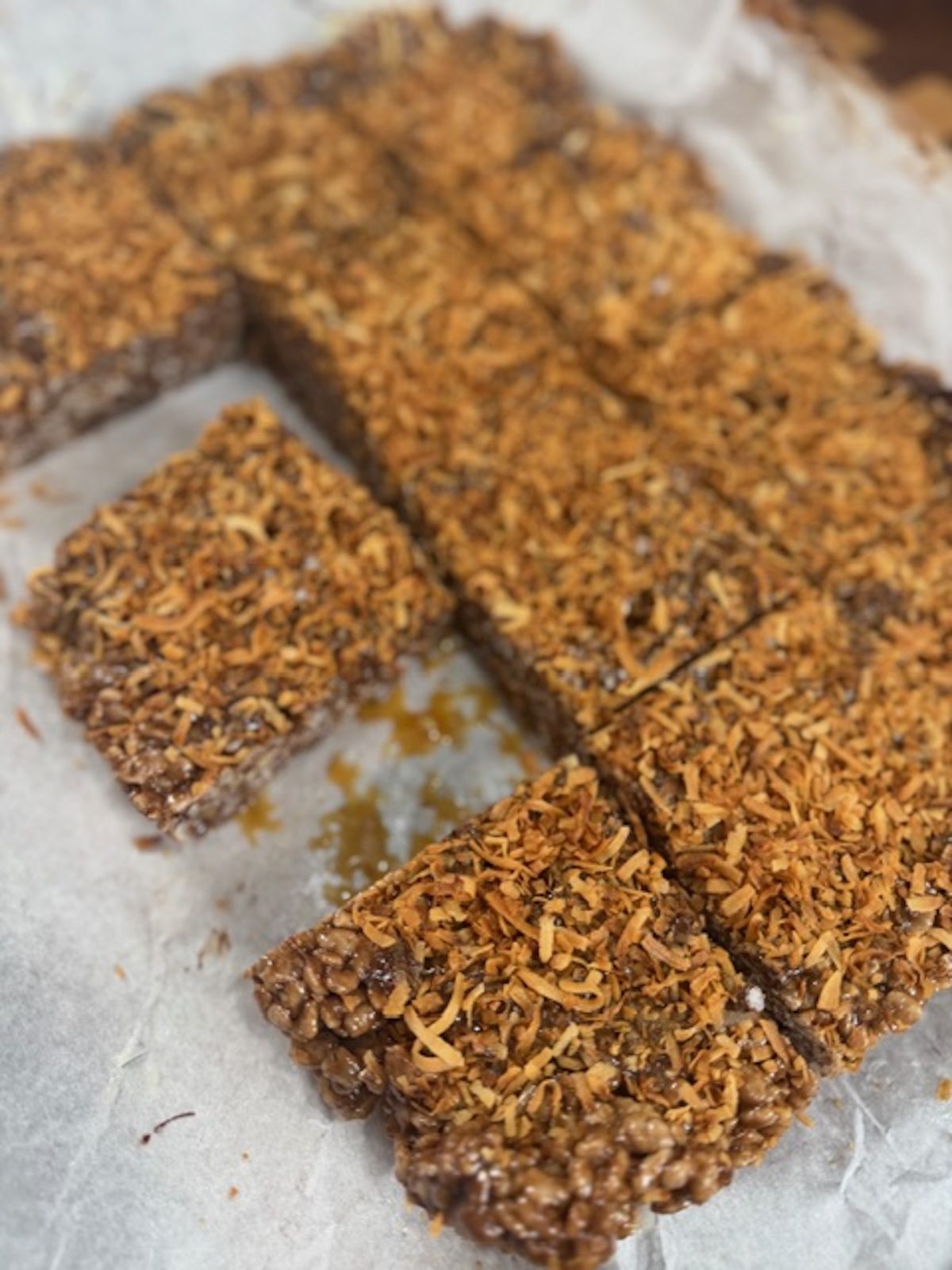 Cut chocolate rice krispie treats cut into squares with toasted coconut on top.