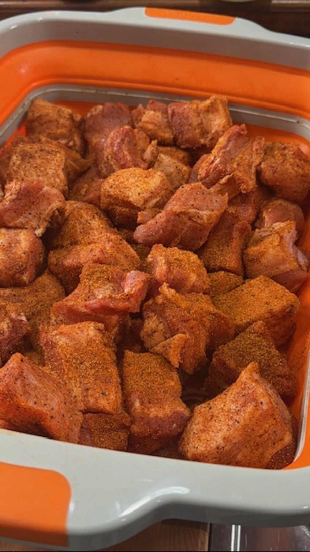 A tub of pork belly burnt ends with seasoning.