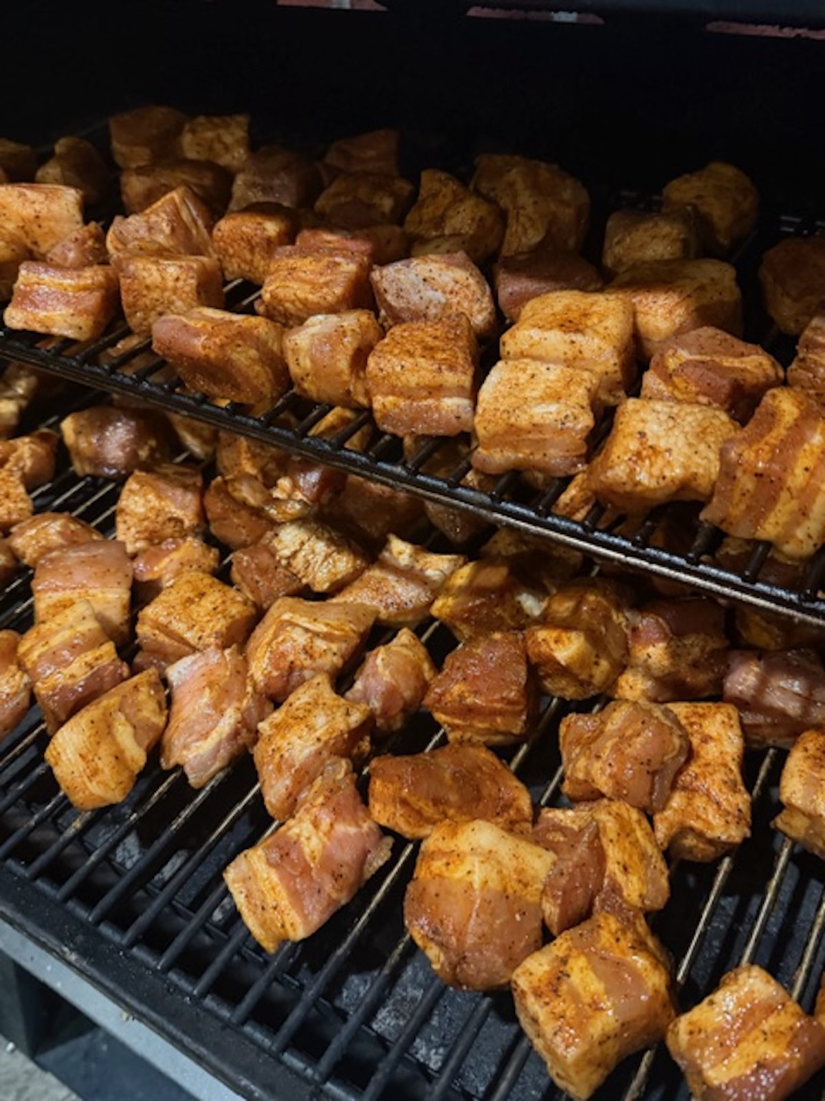 Pork belly burn ends on the smoker about to be cooked.