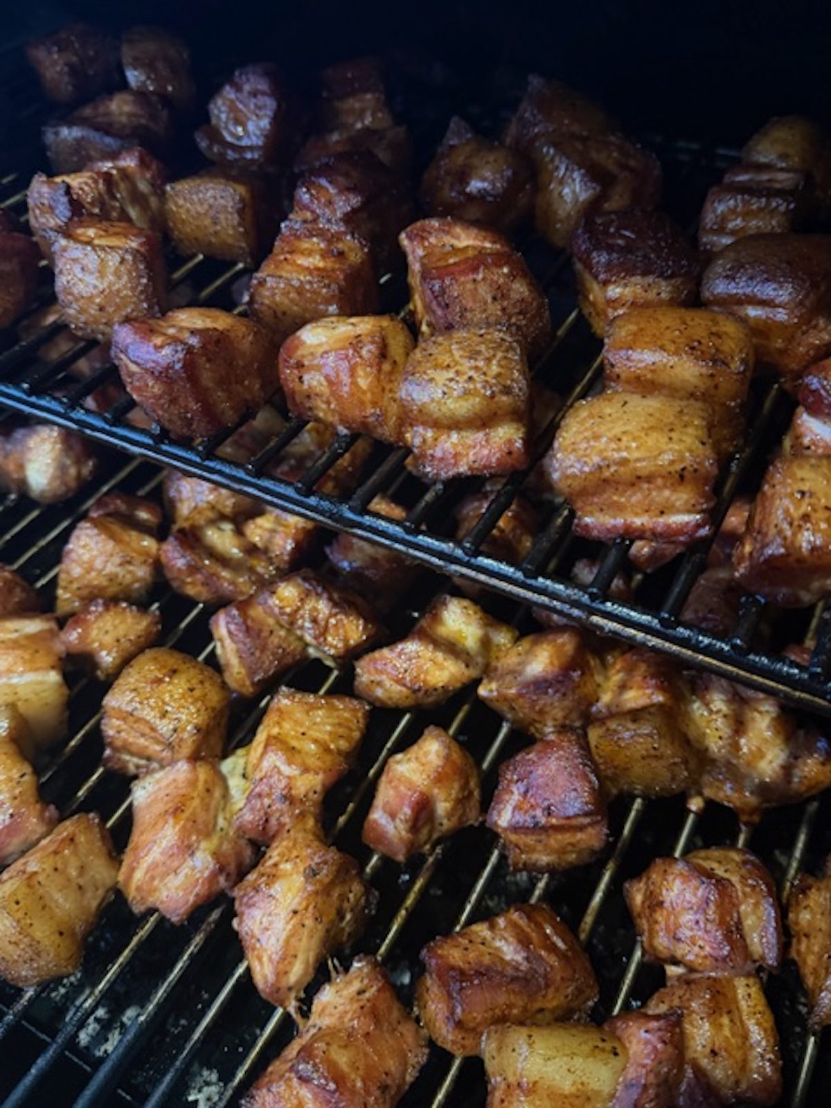 Pork bell burnt ends on two racks of the smoker.