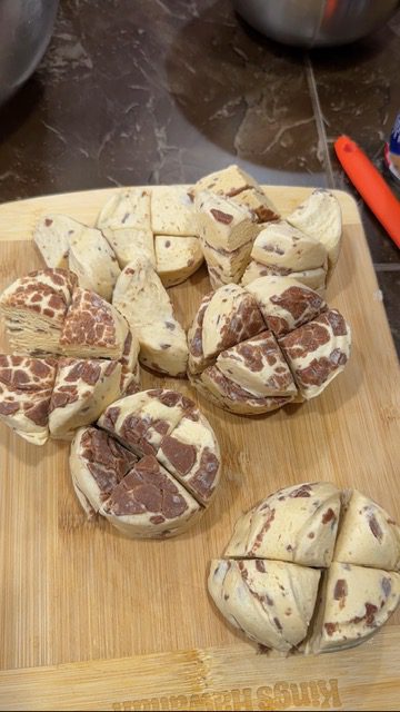 A wooden cutting board with cut canned biscuits.