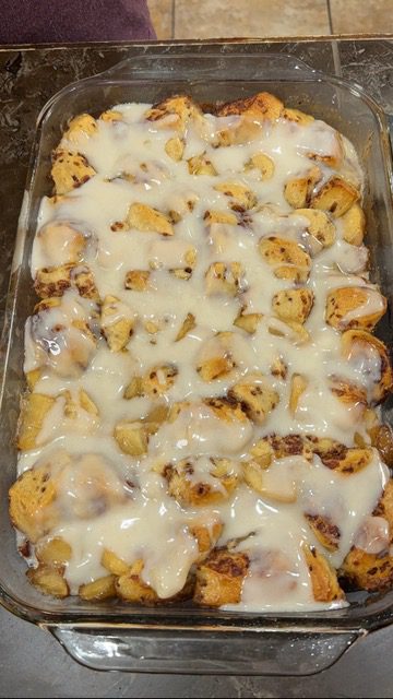A glass baking dish with apple pie bubble bake with icing on top.