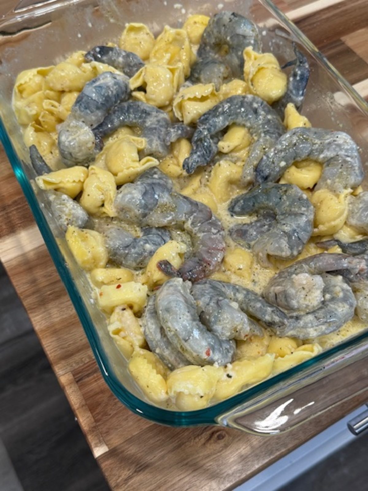 A glass baking dish with tortellini and shrimp.