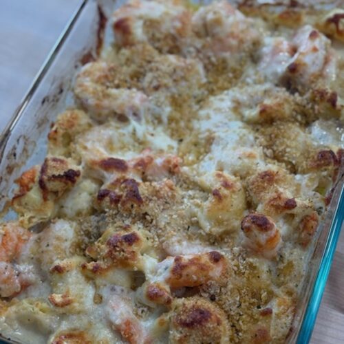 Baked shrimp and tortellini in a glass baking dish.