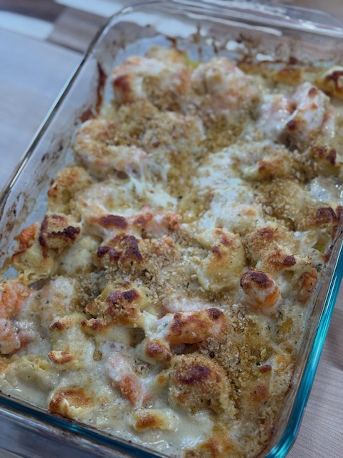 Baked shrimp and tortellini in a glass baking dish.