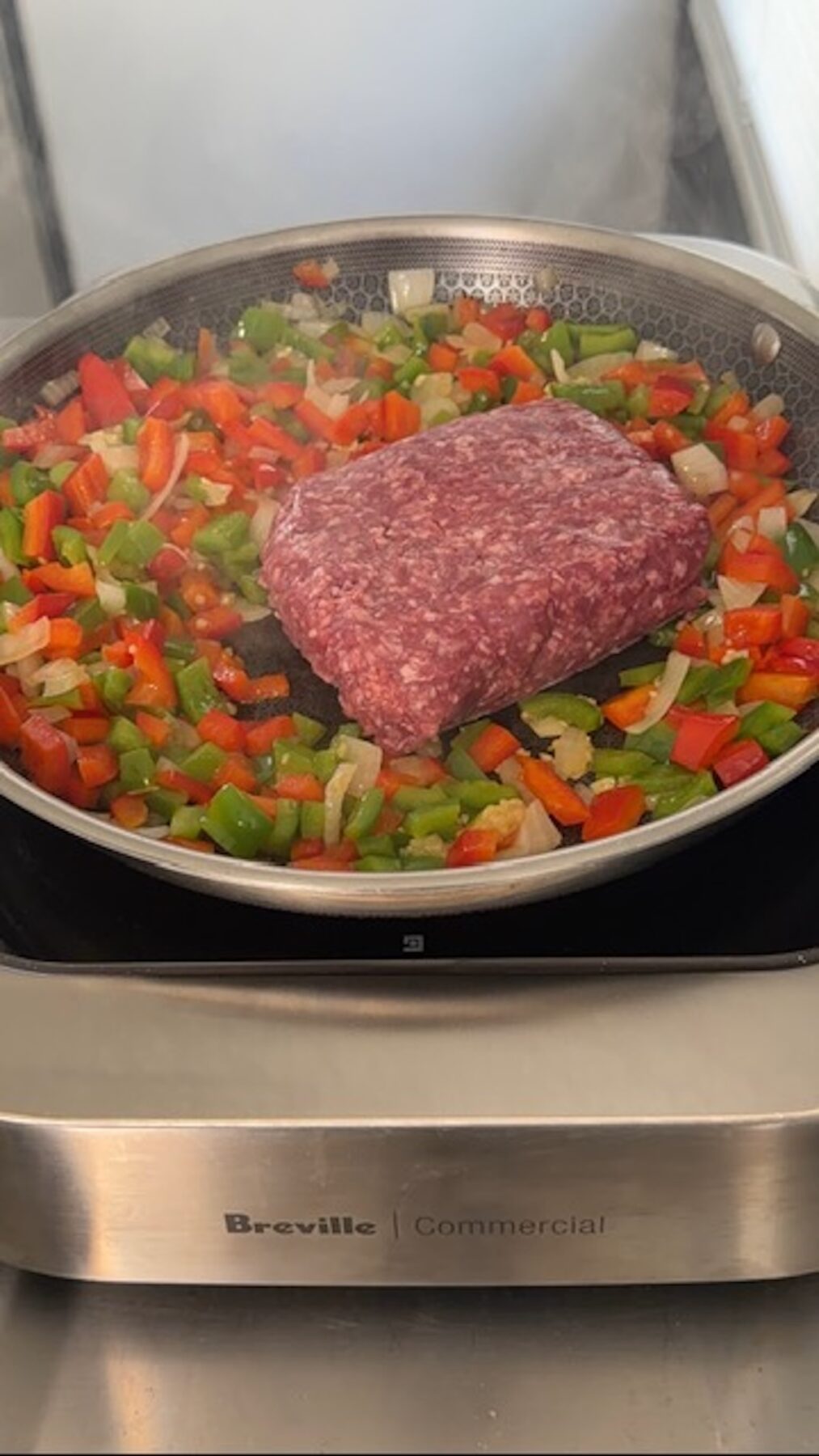ground beef added to pan with peppers and onions cooking