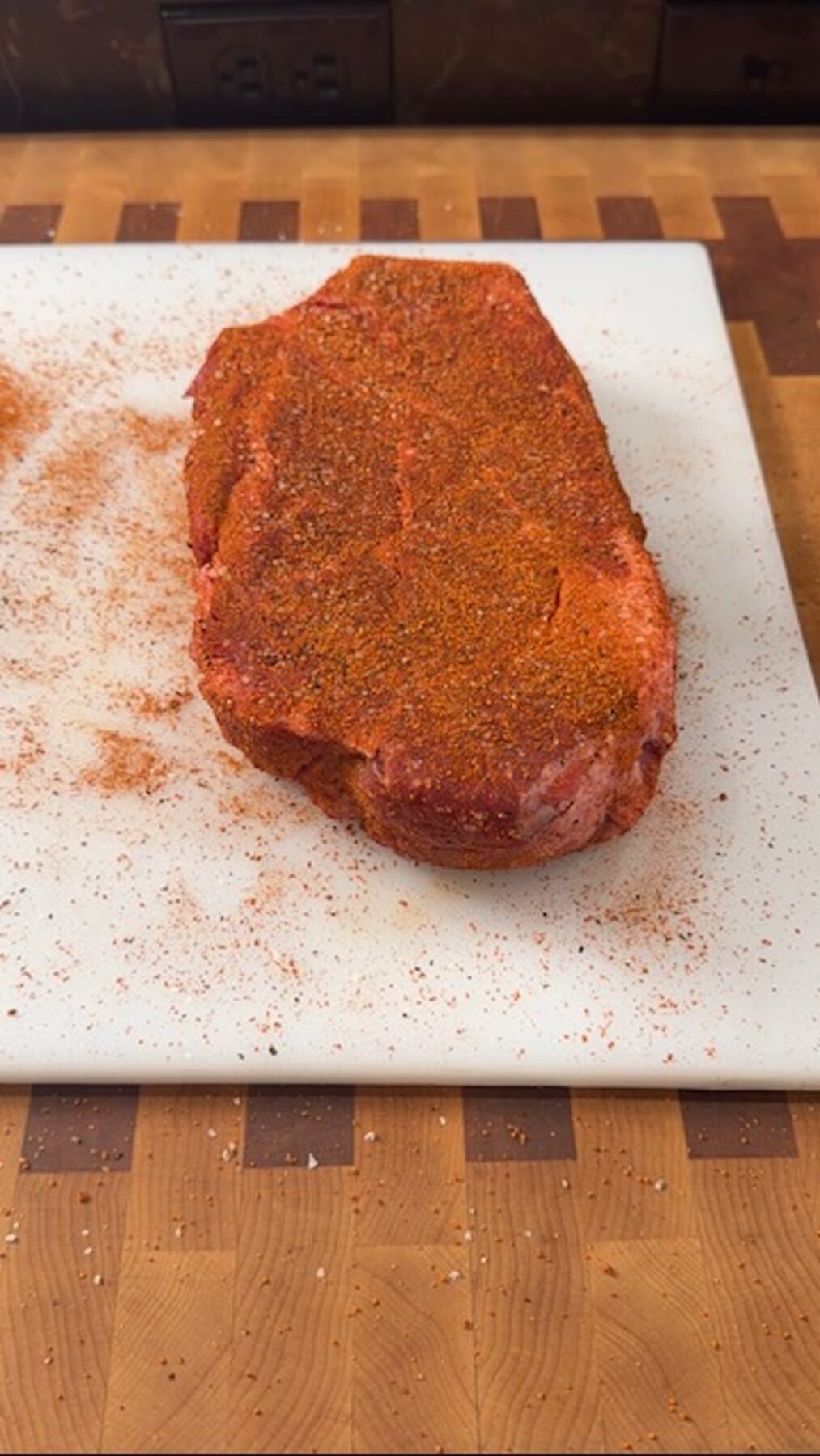 seasoned beef, uncooked, on white cutting board