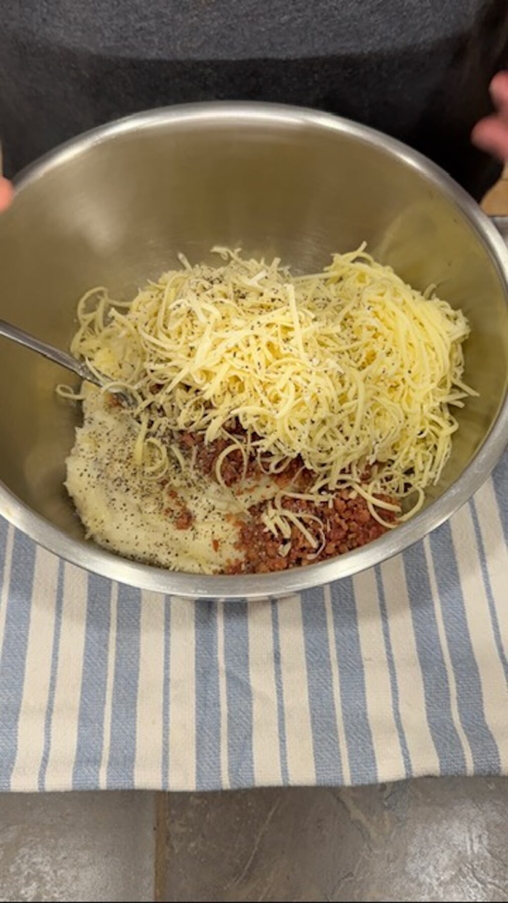 A metal bowl with cheese, spices, and toppings.