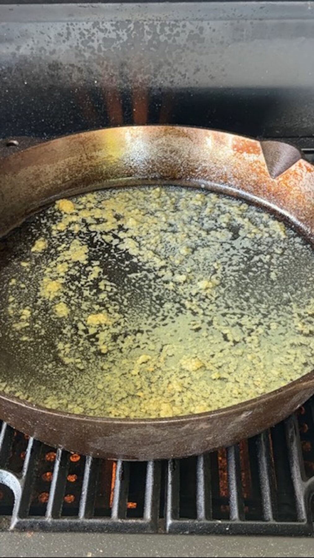 A cast iron on a grill with melted butter.