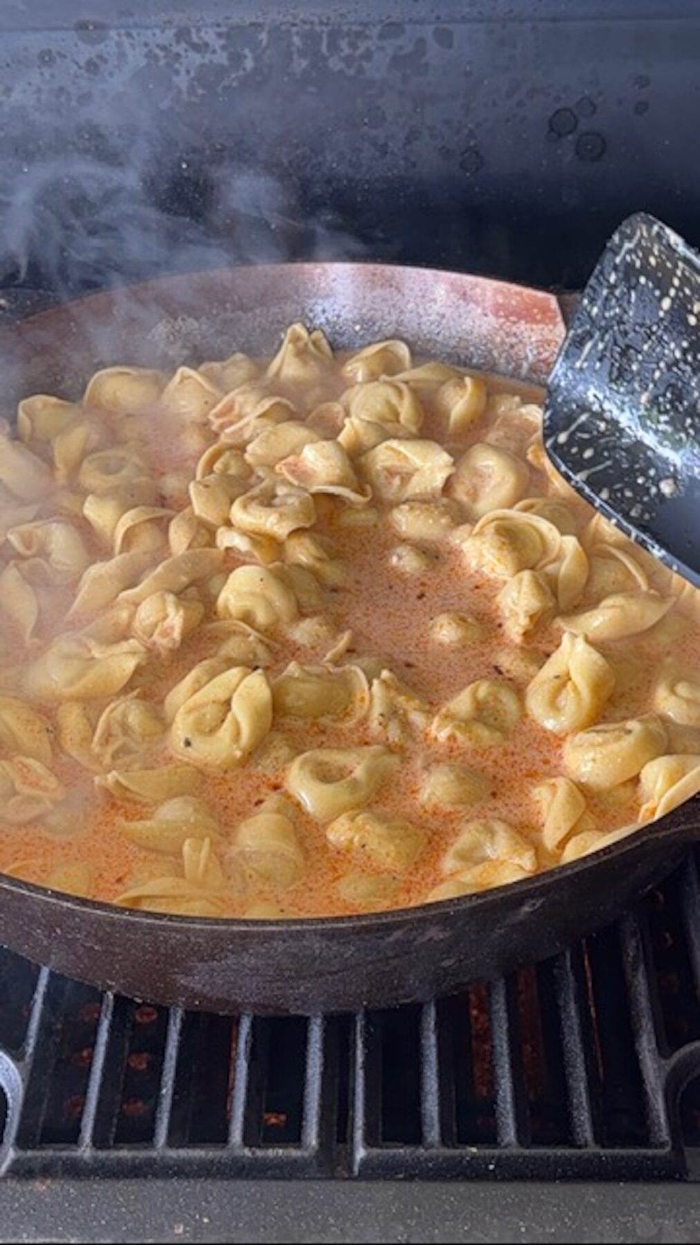 Cast iron with melted butter, spices, and tortellini noodles simmering.