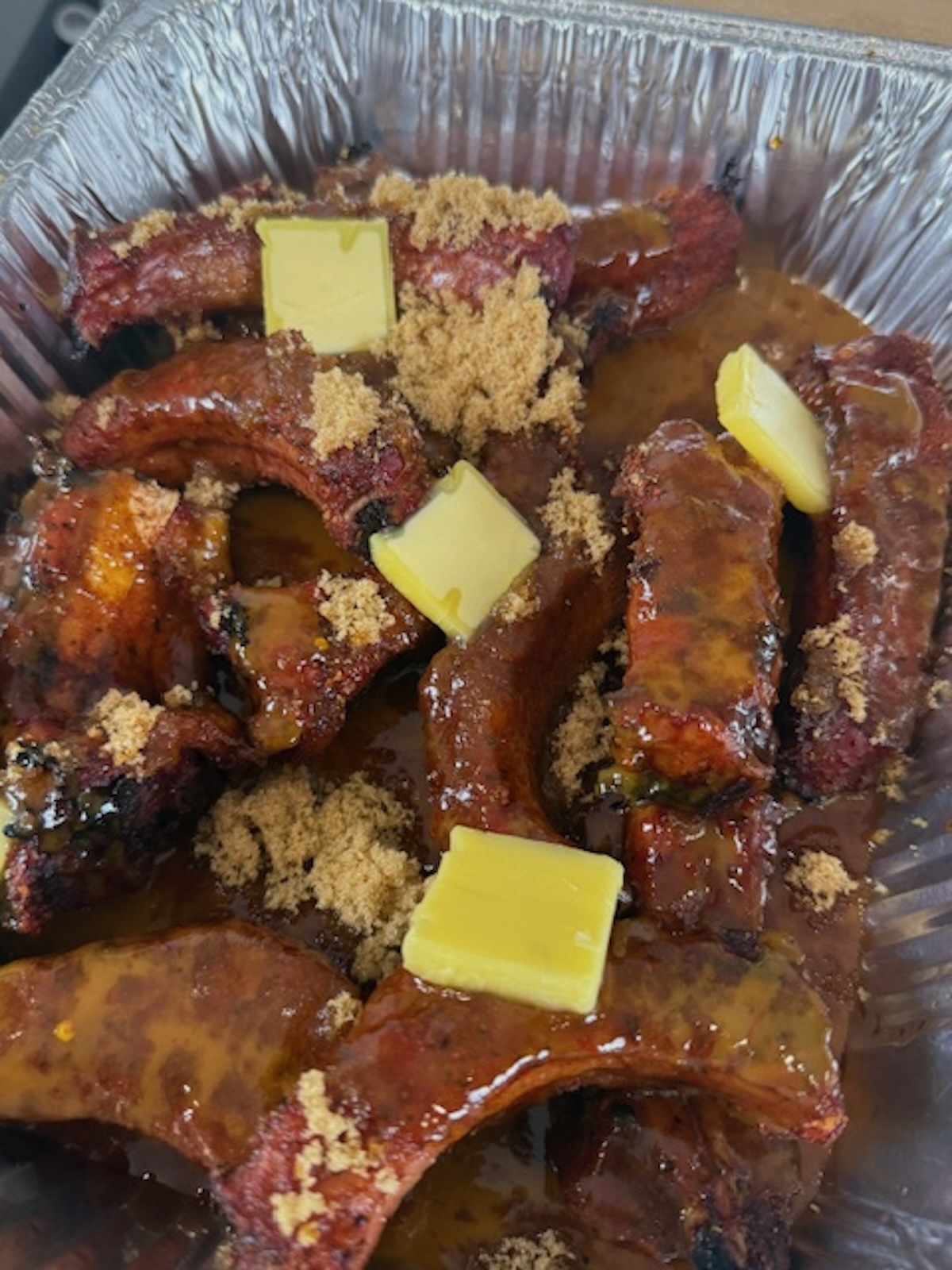 party ribs in foil train topped with brown sugar and pats of butter