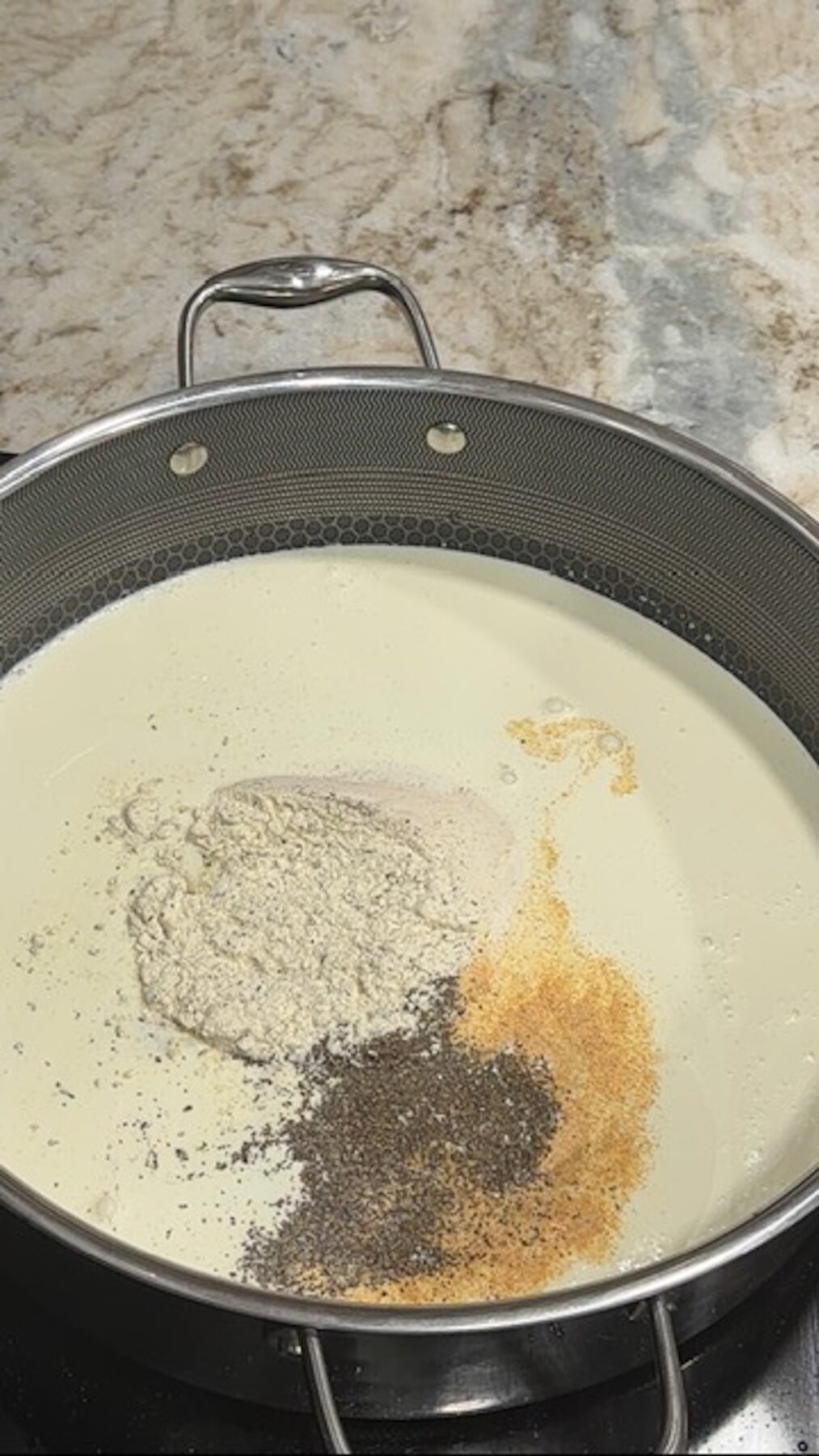 A pot with cream sauce and spices for chicken bacon ranch tortellini.