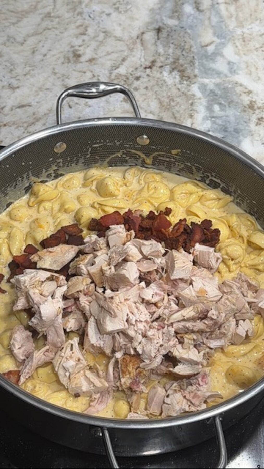 A skillet with chicken, bacon, and tortellini in cream sauce for chicken bacon ranch tortellini.