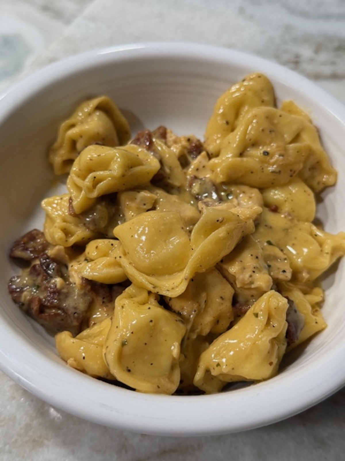 A white bowl with chicken bacon ranch tortellini.