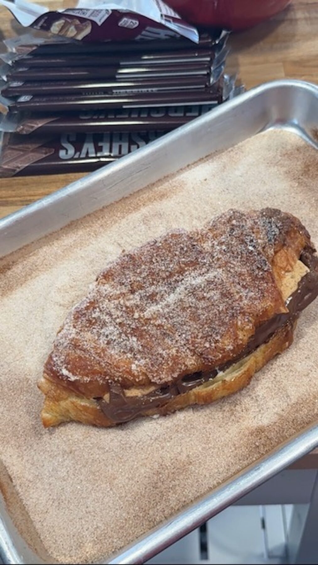 smores churros croissant in cinnamon sugar on sheet pan with chocolate bars in background