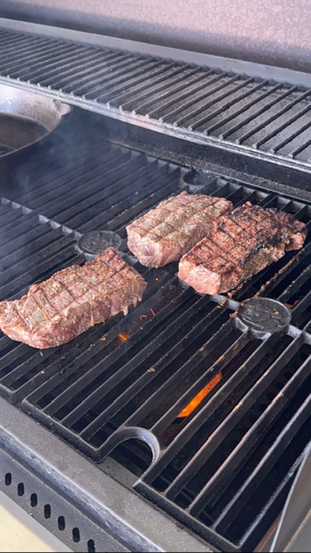 A grill with steaks cooking.
