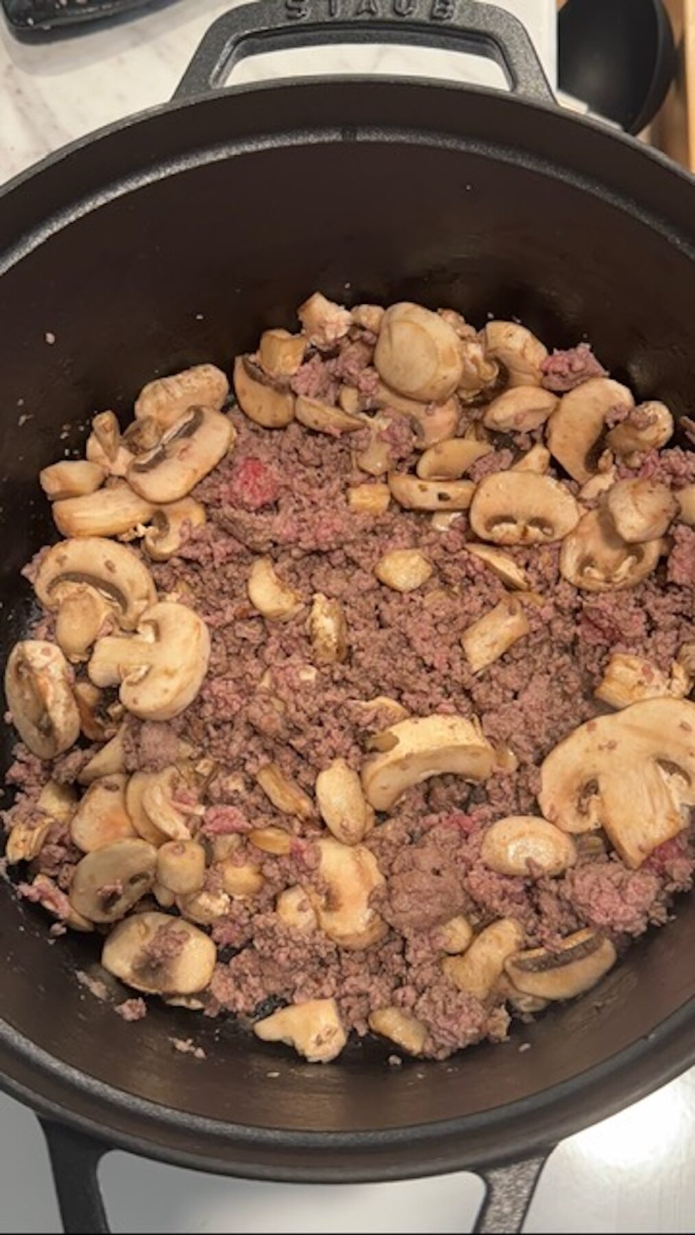 A pot with beef and mushrooms cooking.