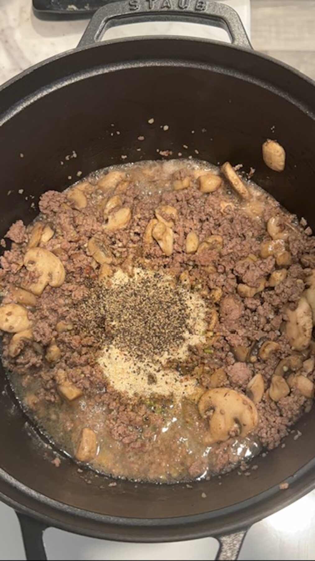 A pot with beef, mushrooms, garlic and seasonings cooking.