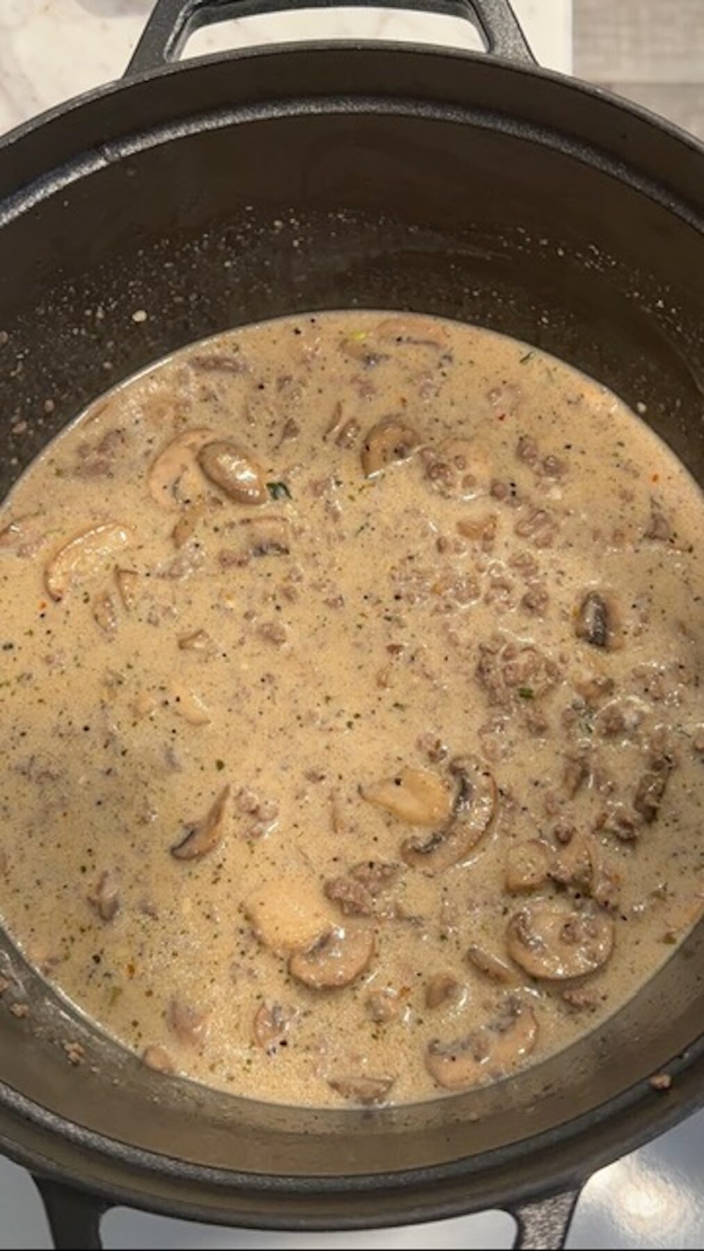 A pot with beef, mushrooms, and cream sauce cooking.