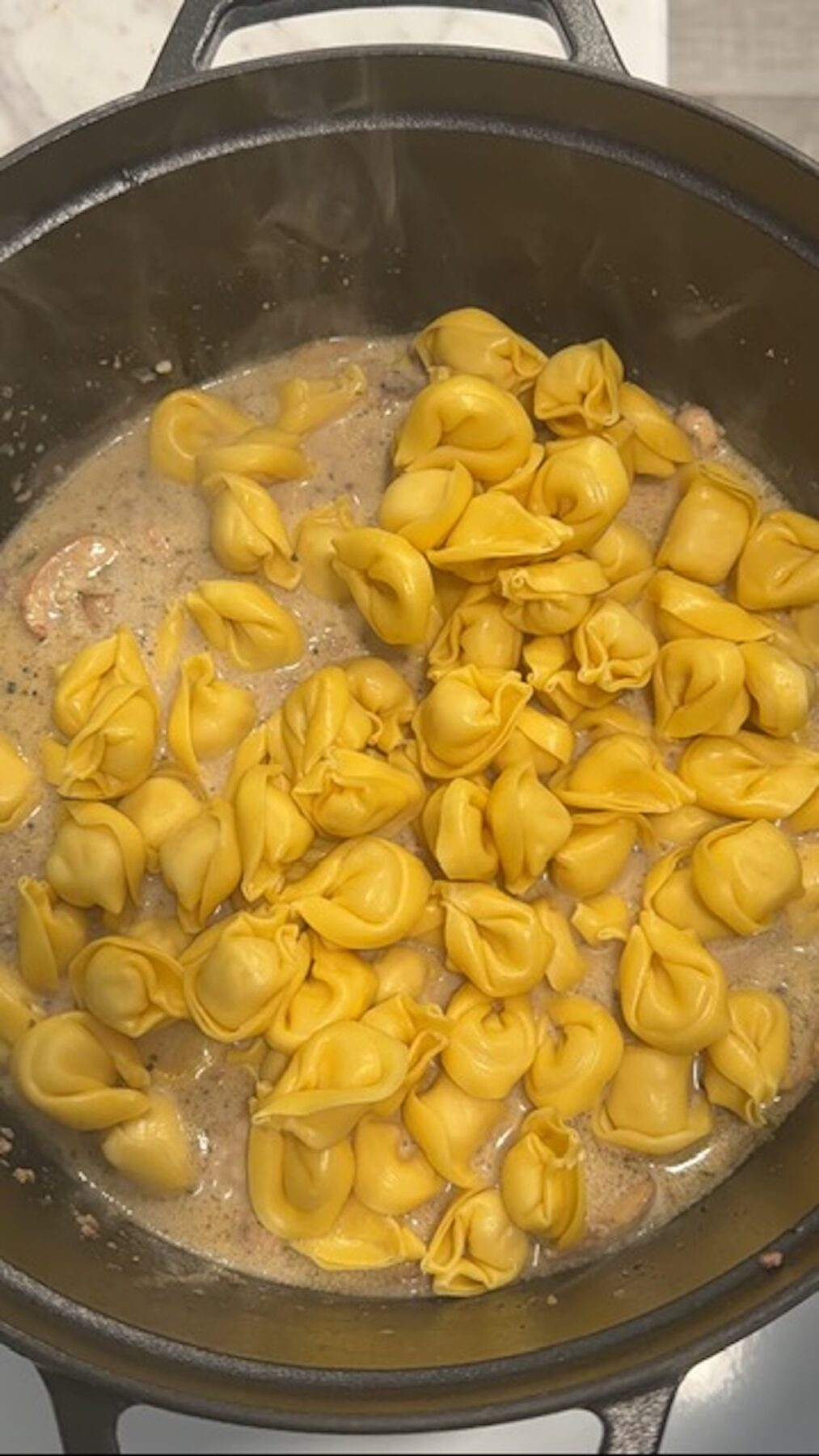 A pot with tortellini noodles, cream sauce, beef and mushroom sauce for beef and tortellini.