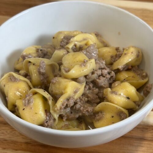 A white bowl with beef stroganoff tortellini.