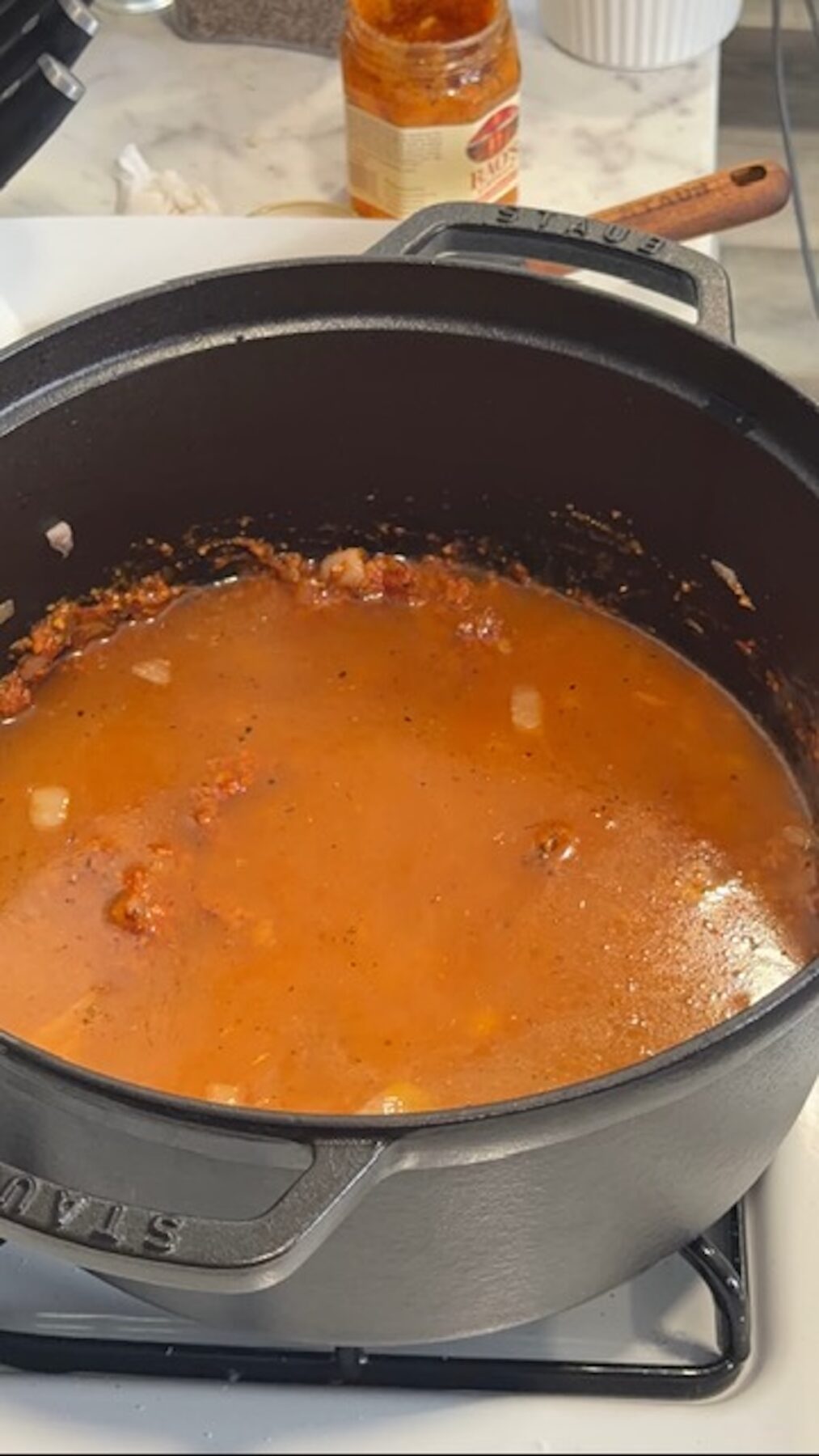 broth base with tomato paste in pot for marry me chicken potato soup