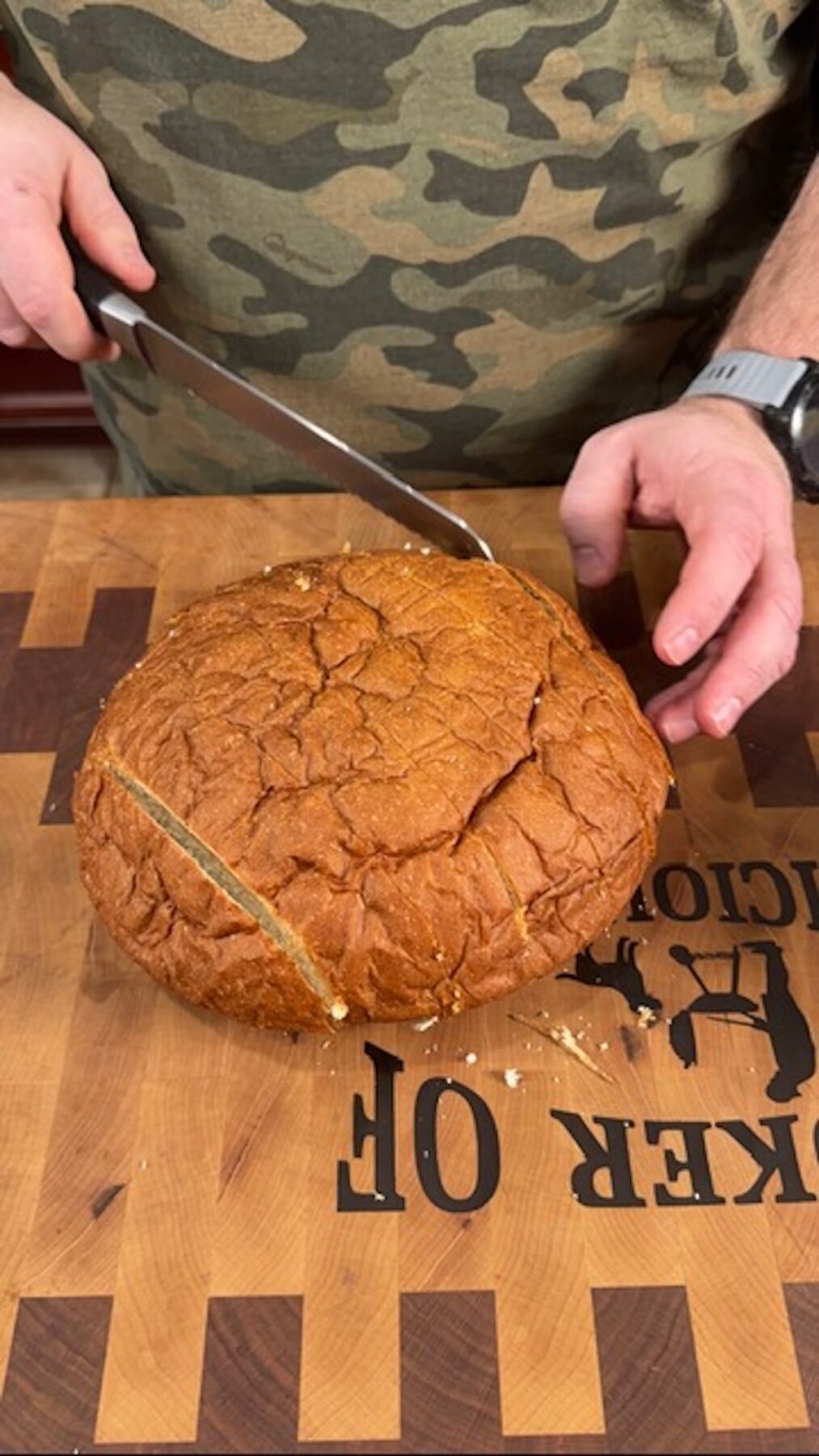 A knife cutting a loaf of bread for cheesy pull apart bread.