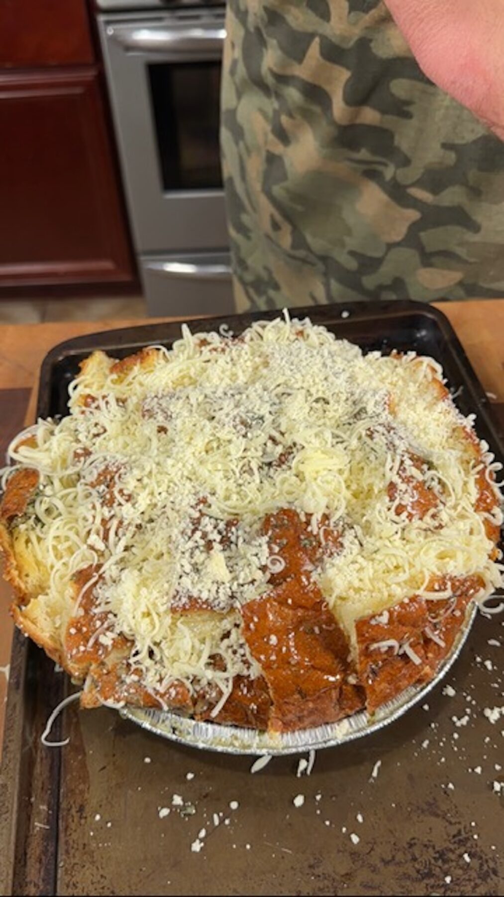 A baking sheet with a loaf of bread with shredded cheese on top.