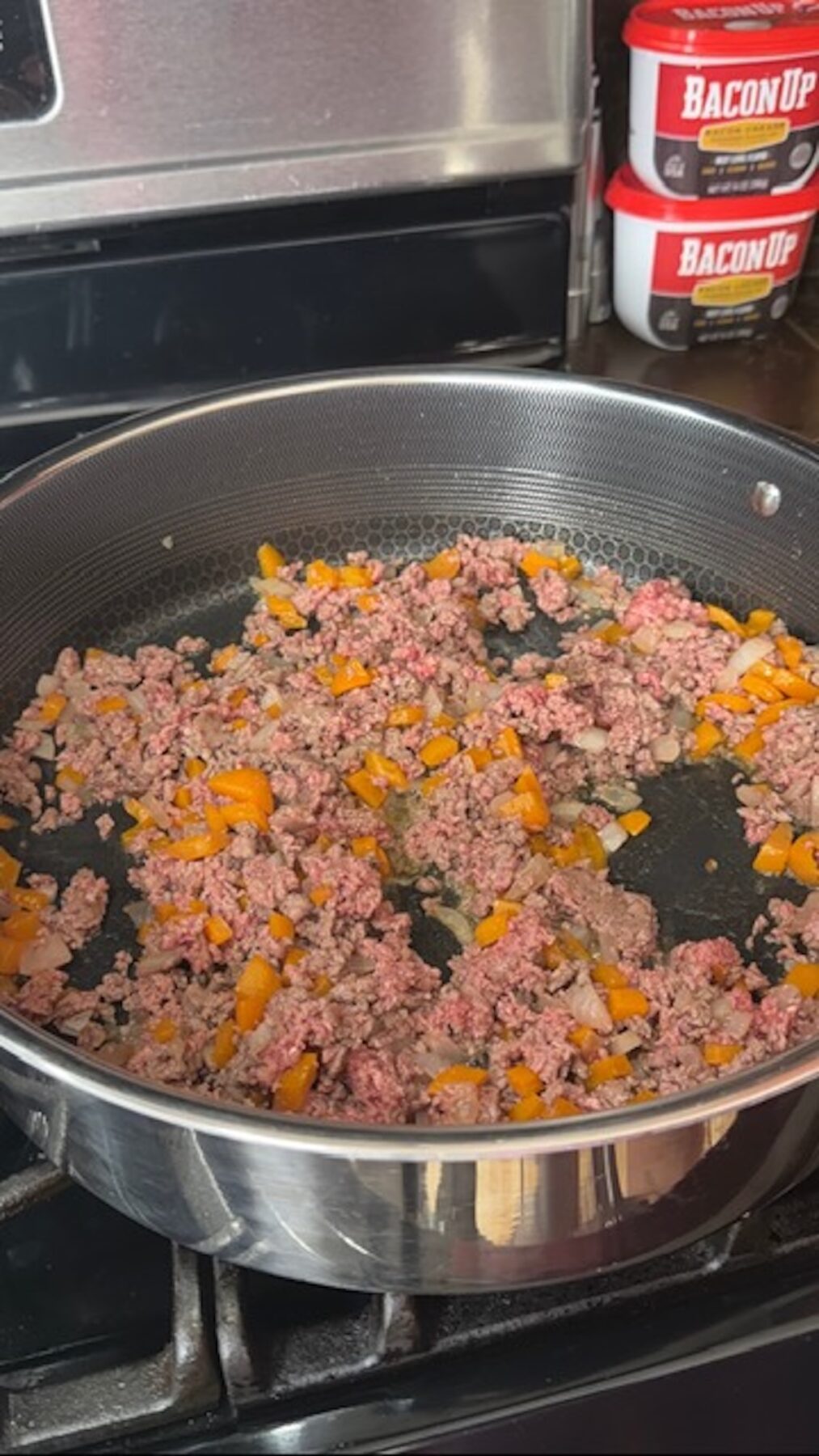 Ground beef mixture and veggies being browned and cooked in pan on stove